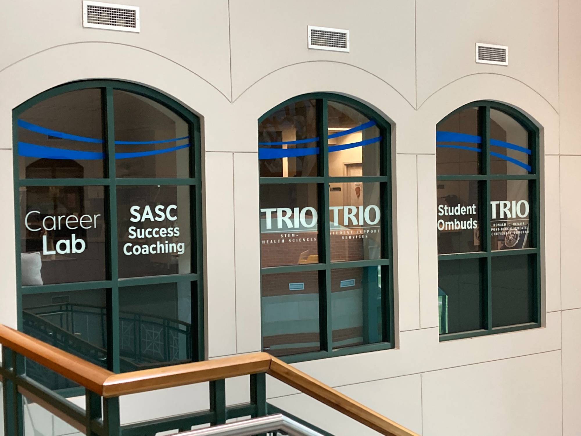 Stairs and window outside of the Student Academic Success Center Office Suite. Windows list Career Lab, SASC Success Coaching, TRIO and Student Ombuds